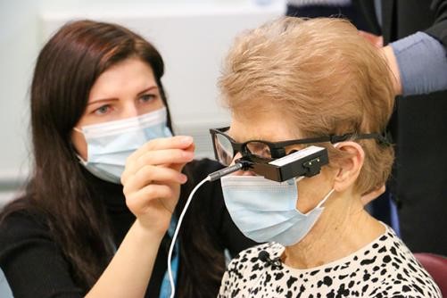 Patient with 'bionic eye' sitting with consultant adjusting glasses