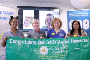 Four nurses holding the Daisy Award banner smiling at the camera