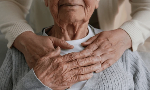 Hands gently placed on the shoulders of someone sitting down