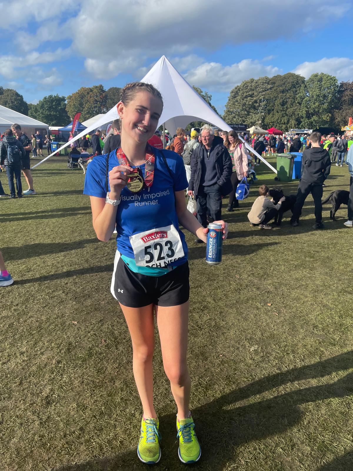 Lily in her running gear holding her medal