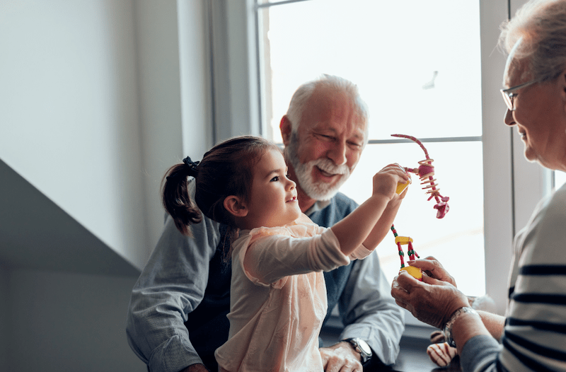 Grandparents and their grandchild sitting next to a window playing with small animal toys