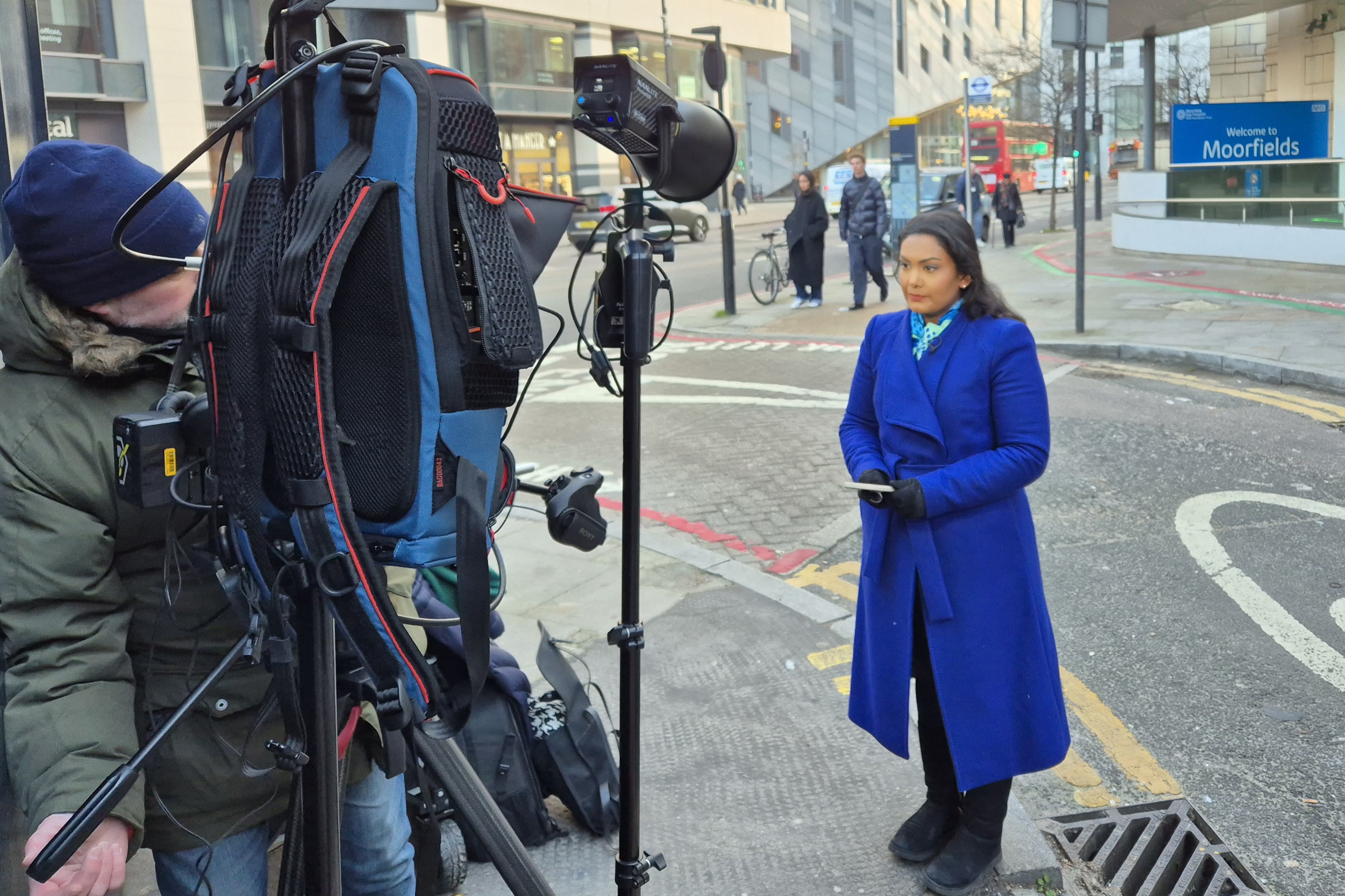 Person in a blue coat speaking to a TV camera outside City Road Moorfields 