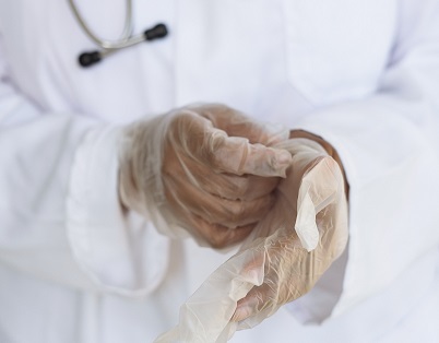 A health practitioner putting on surgical gloves