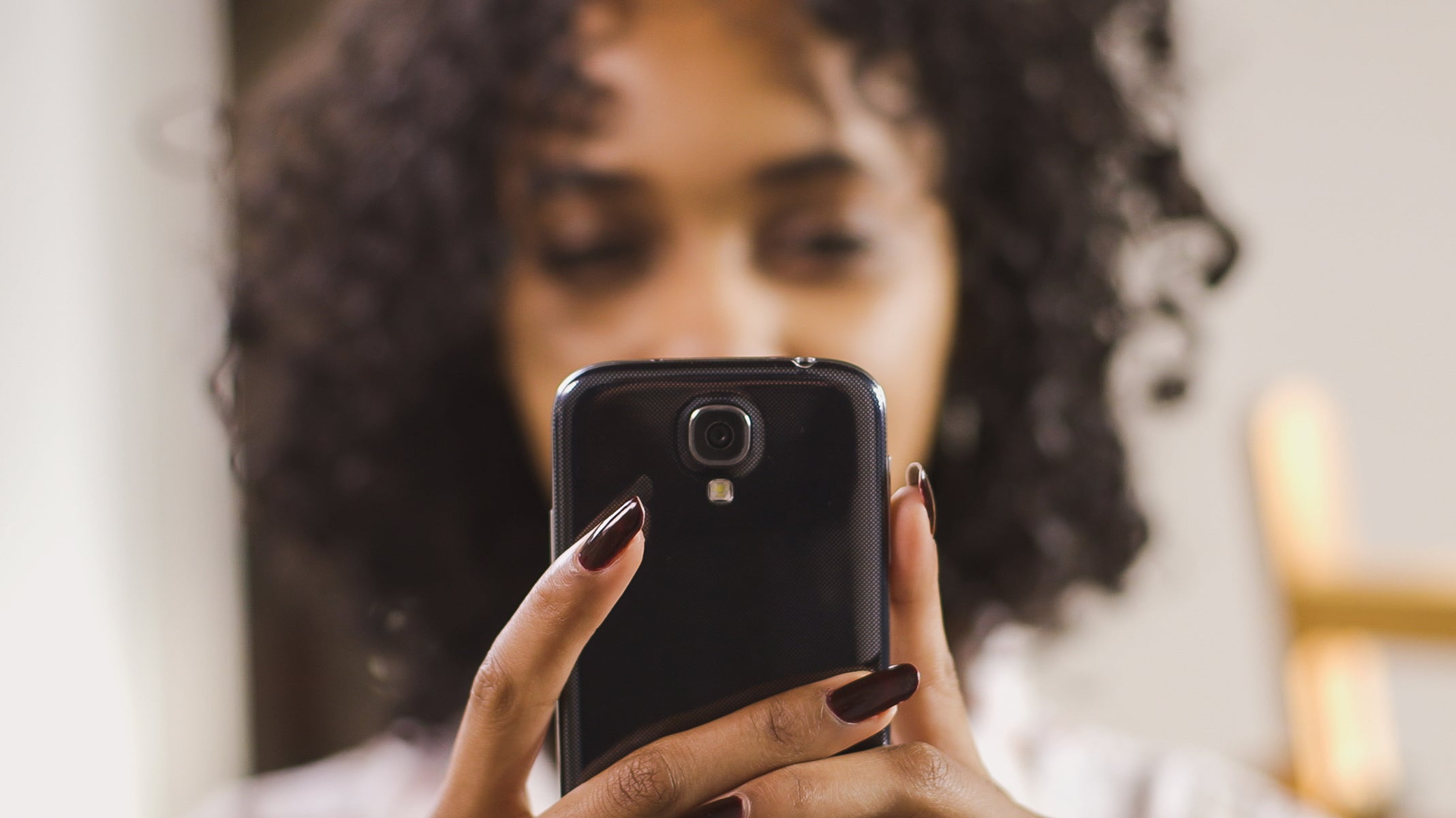 Blurred image of a person holding their mobile phone, the mobile phone is in focus in the foreground