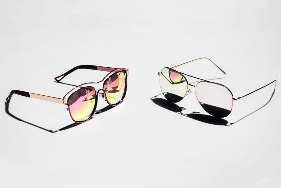 Two pairs of reflective sunglasses on a grey background