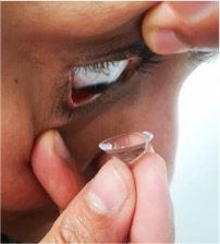 Person looking down and inserting a contact lens with a device