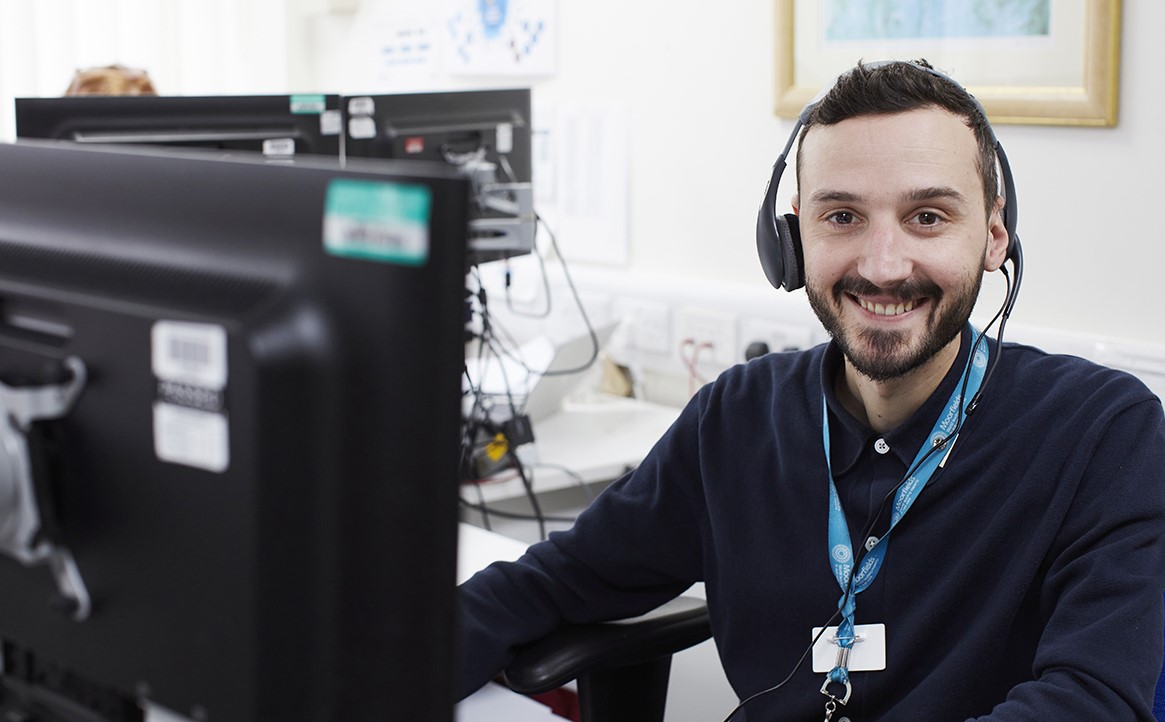 Member of Moorfields staff behind a computer with a phone headset on