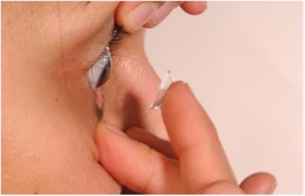 Fingertips inserting a contact lens into an eye