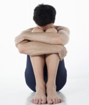 Person curled up in a ball with their arms around their legs and their head on their knees