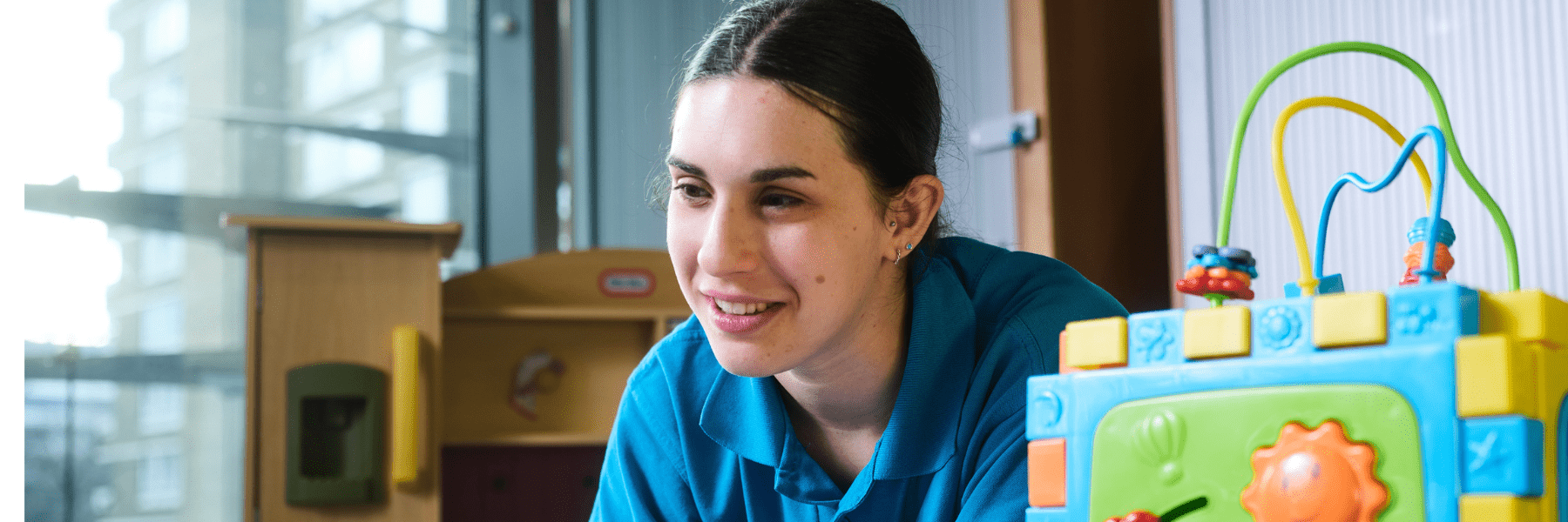 Jemma, a staff member in the paediatric centre, caring for children with a blue toy
