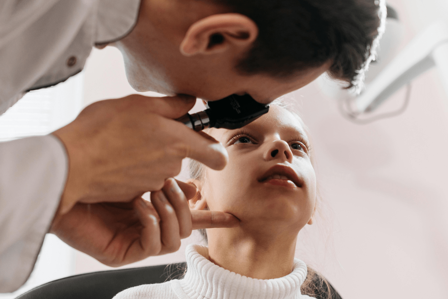 Ophthalmologist examining a child's eyes with a light